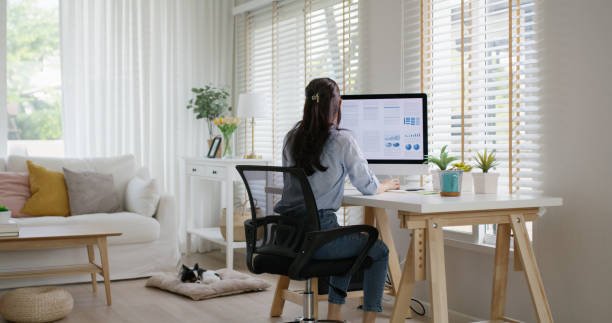 Young Asian woman working from home on desktop PC, analyzing big data for SEO sales report.