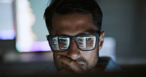 Hispanic Latin American male software engineer coding on a computer at his home office at night, focused on developing software.