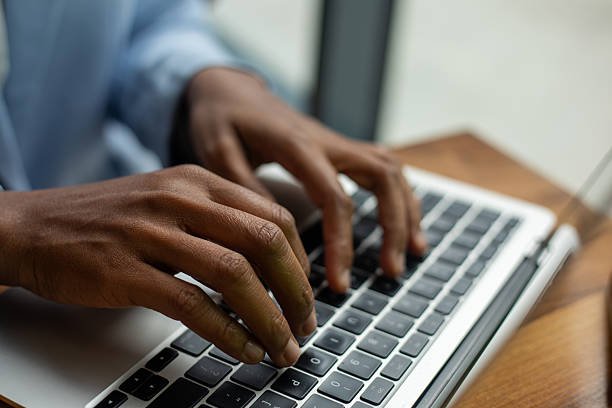 Close-up of hands typing on a laptop keyboard in an office setting.