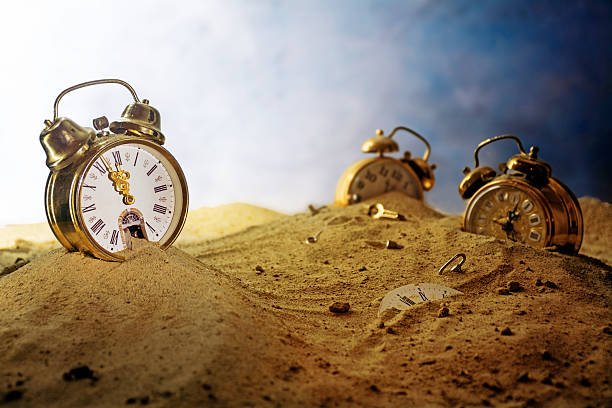 Surreal scene of sand running out of a nostalgic alarm clock while other watches sink into the sand in a fantasy landscape, symbolizing the passage of time.