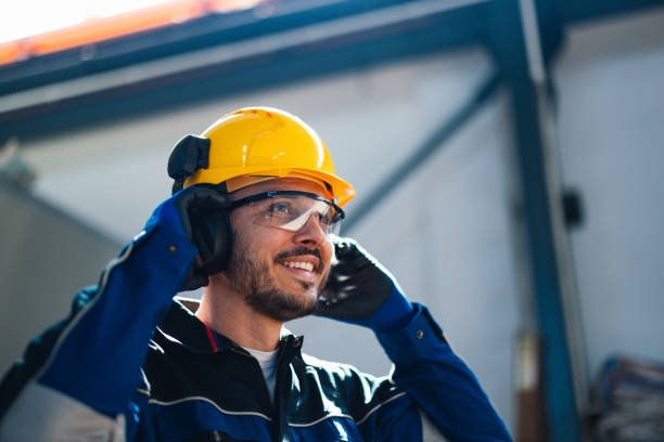 smiling worker in safety helmet communicating in factory